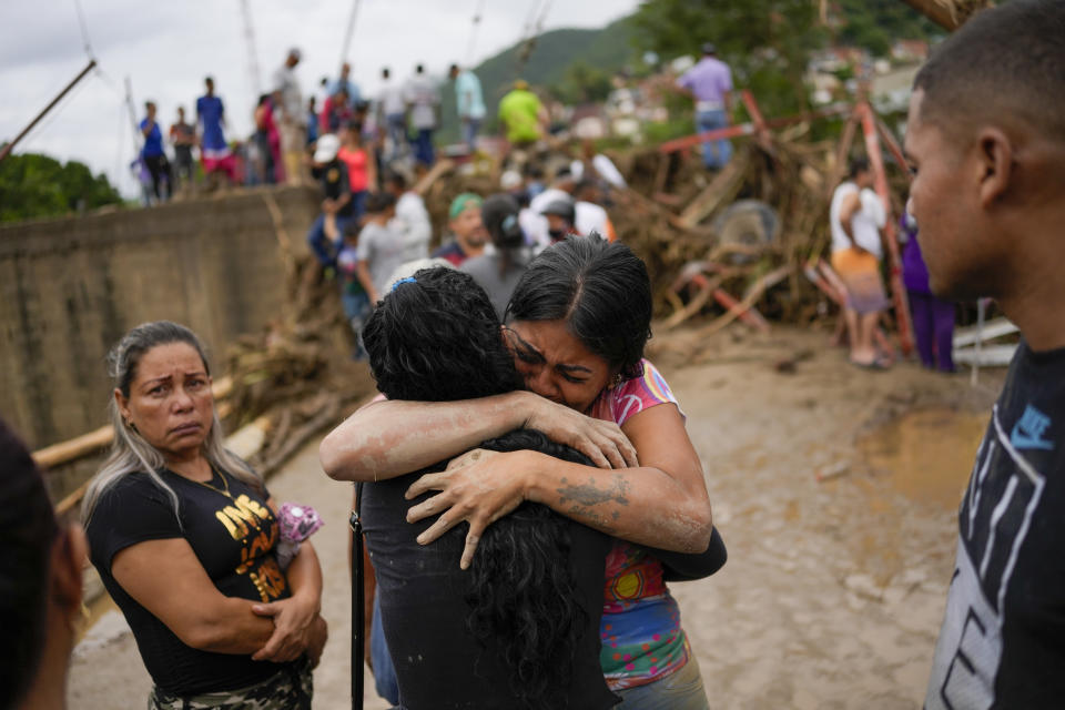 Residents embrace in Las Tejerias, Venezuela, Sunday, Oct. 9, 2022, after intense rain caused a river to overflow flooding the town. (AP Photo/Matias Delacroix)