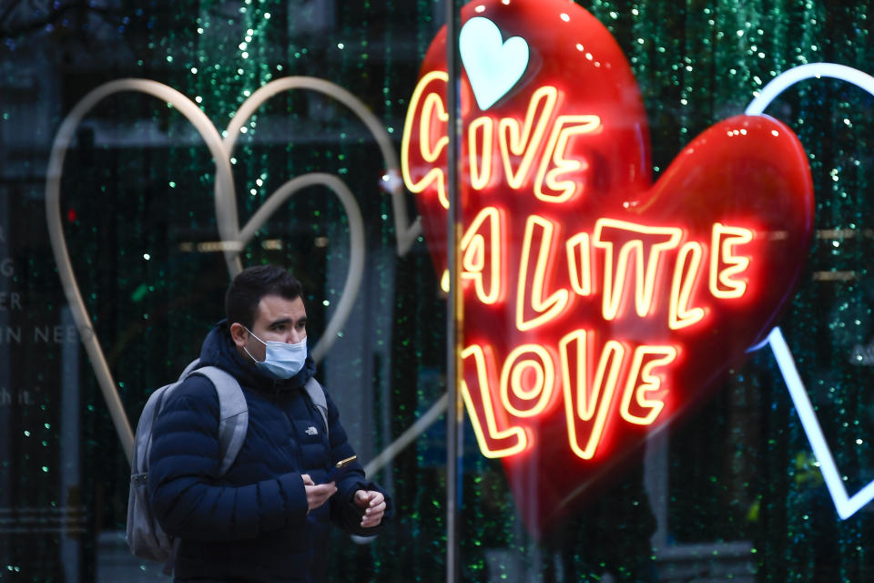 A man wears a face mask as he walks past a shop window in Oxford Street, in London, Tuesday, Nov. 24, 2020. Haircuts, shopping trips and visits to the pub will be back on the agenda for millions of people when a four-week lockdown in England comes to an end next week, British Prime Minister Boris Johnson said Monday. (AP Photo/Alberto Pezzali)