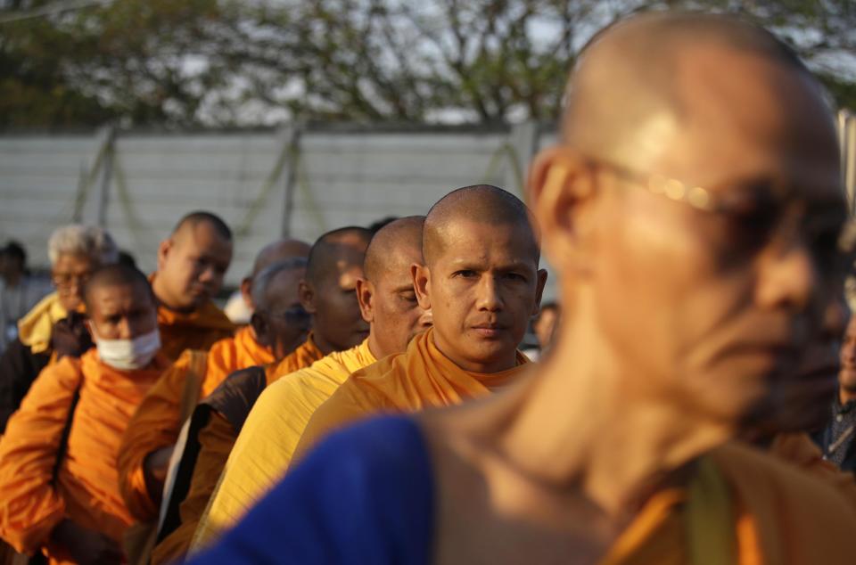 Buddhist monks stand in front of policemen outside the Wat Dhammakaya temple in Pathum Thani province, Thailand, Thursday, Feb. 16, 2017. Hundreds of police in Thailand are carrying out a raid on the headquarters temple of a controversial Buddhist temple sect to detain its chief, a monk facing criminal charges including accepting $40 million in embezzled money. (AP Photo/Sakchai Lalit)
