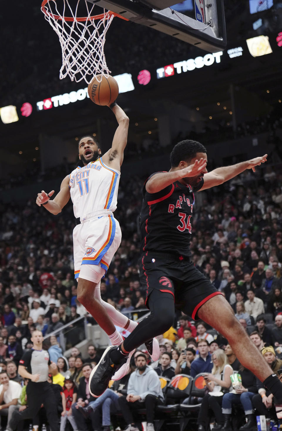 Oklahoma City Thunder guard Isaiah Joe (11) dunks as Toronto Raptors centre Jontay Porter (34) defends during the second half of an NBA basketball game Friday, March 22, 2024, in Toronto. (Nathan Denette/The Canadian Press via AP)