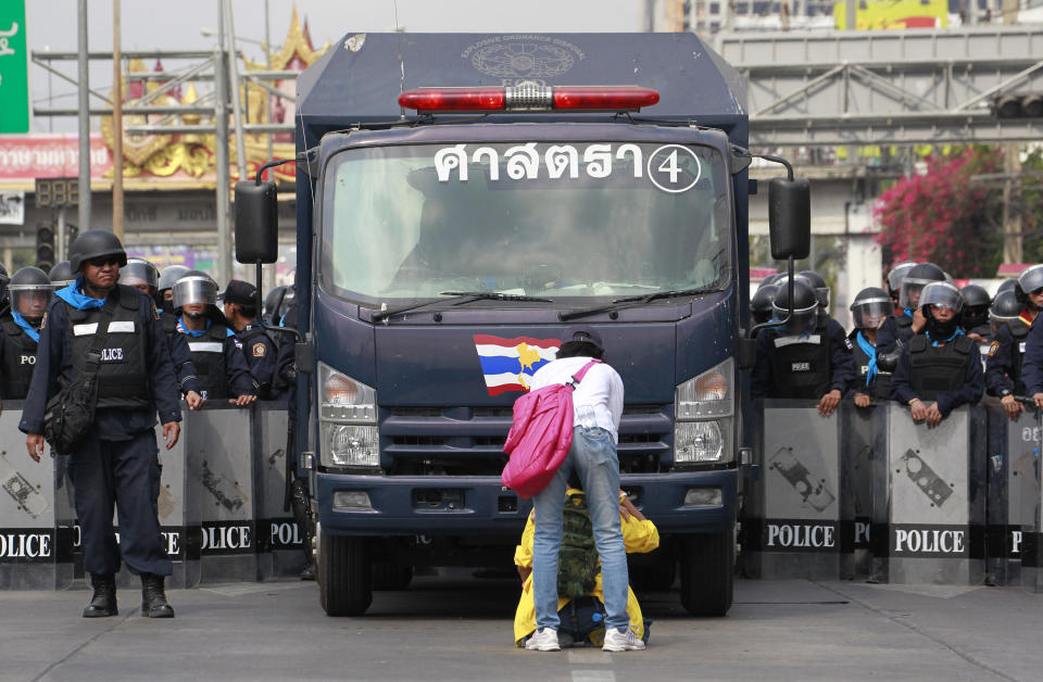 Anti-government protesters block the way of a police truck carrying police officers for an operation to reclaim government offices occupied by anti-government protesters on the outskirts of Bangkok, Thailand Friday, Feb. 14, 2014. Riot police cleared anti-government protesters from a major boulevard in the Thai capital in a small victory for authorities Friday as they try to reclaim areas that have been closed during a three-month push to unseat Prime Minister Yingluck Shinawatra. (AP Photo/Wason Wanichakorn)