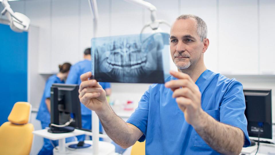 Mature male orthodontist looking at X-ray image.