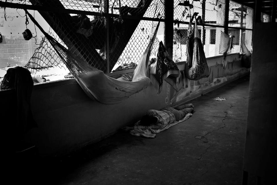 Inmates at seen sleeping in makeshift hammocks and on the ground below.