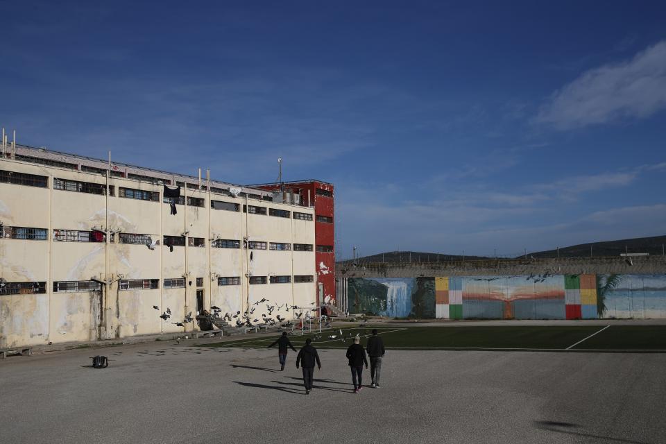 Inmates walk in the yard of Avlona prison, north of Athens, Wednesday, Feb. 10, 2021. With Greece's schools shut due to the pandemic, all lessons have gone online. But the online world isn't within reach of everyone _ and particularly not within reach of the students of Avlona Special Youth Detention Center, where internet devices are banned by law from the cells. (AP Photo/Thanassis Stavrakis)