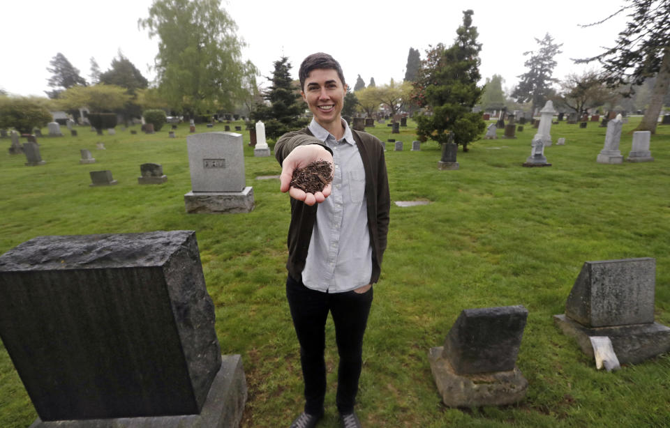 In this Friday, April 19, 2019, photo Katrina Spade, the founder and CEO of Recompose, displays a sample of the compost material left from the decomposition of a cow, using a combination of wood chips, alfalfa and straw, as she poses in a cemetery in Seattle. Spade hopes to use the process, which accelerates natural decomposition when placed in a temperature and moisture-controlled vessel that is rotated, to compost human bodies. (AP Photo/Elaine Thompson)