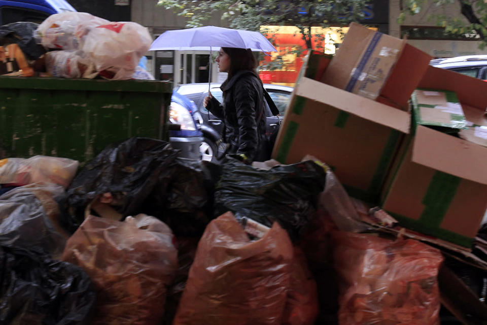 A woman passes a pile of garbage during on-going mobilizations by municipal workers in the northern Greek port city of Thessaloniki.