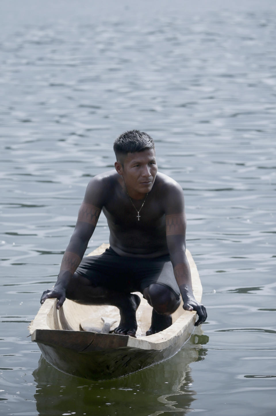 In this Nov. 25, 2018 photo, an Embera man sits on a wooden dugout canoe during the second edition of the Panamanian indigenous games on Lake Bayano, Panama. The games began with swimming and boating in Lake Bayano. (AP Photo/Arnulfo Franco)