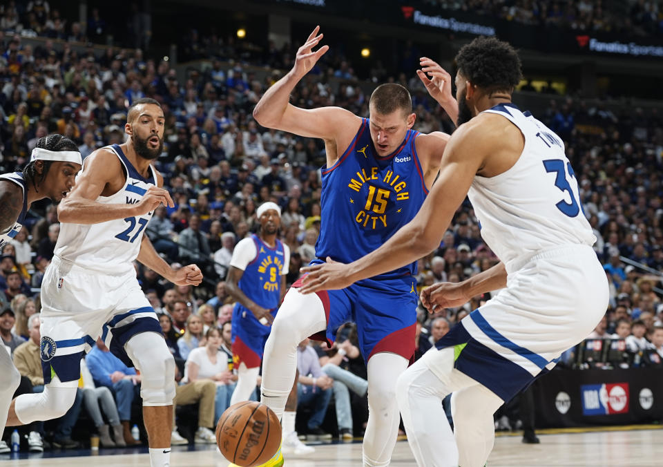 Denver Nuggets center Nikola Jokic, center, loses control of the ball while driving to the basket between Minnesota Timberwolves centers Rudy Gobert, left, and Karl-Anthony Towns in the first half of Game 1 of an NBA basketball second-round playoff series Saturday, May 4, 2024, in Denver. (AP Photo/David Zalubowski)