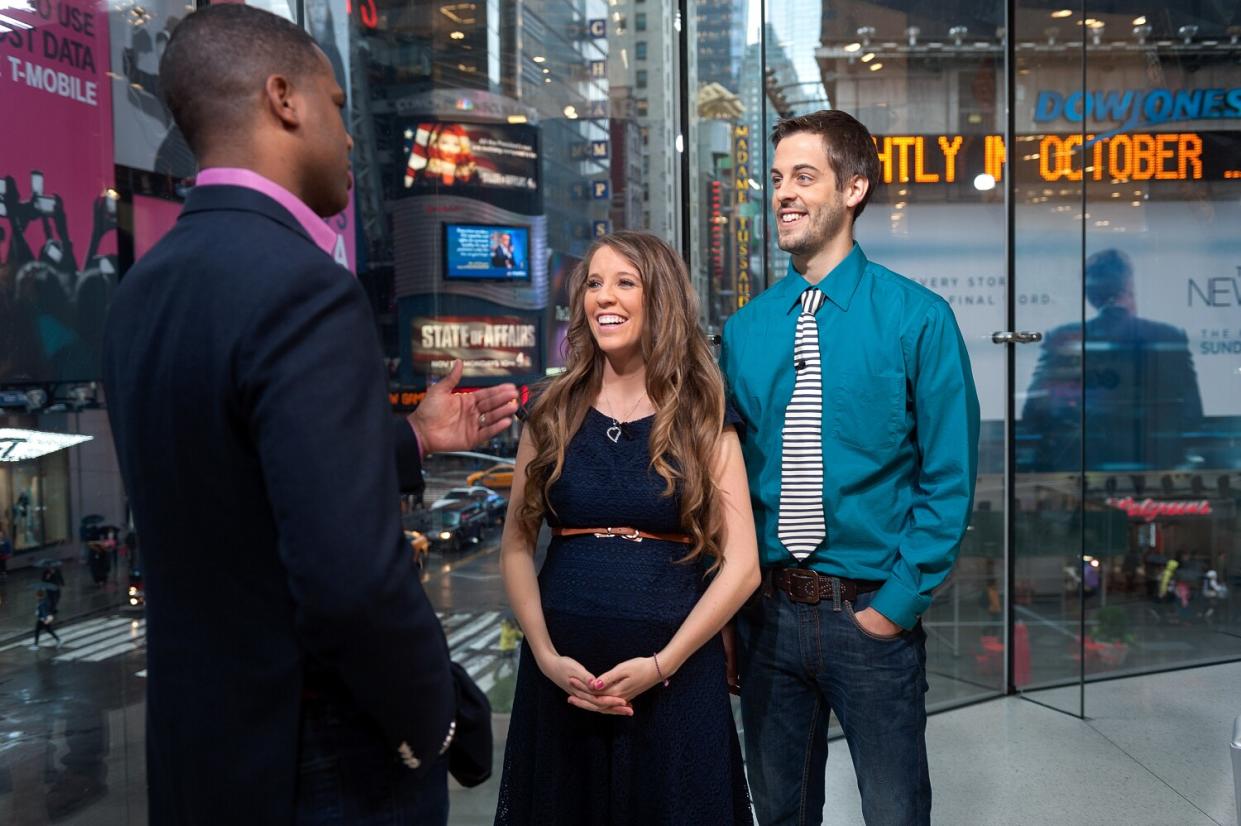 A man in a suit interviews a young couple in a New York City studio.