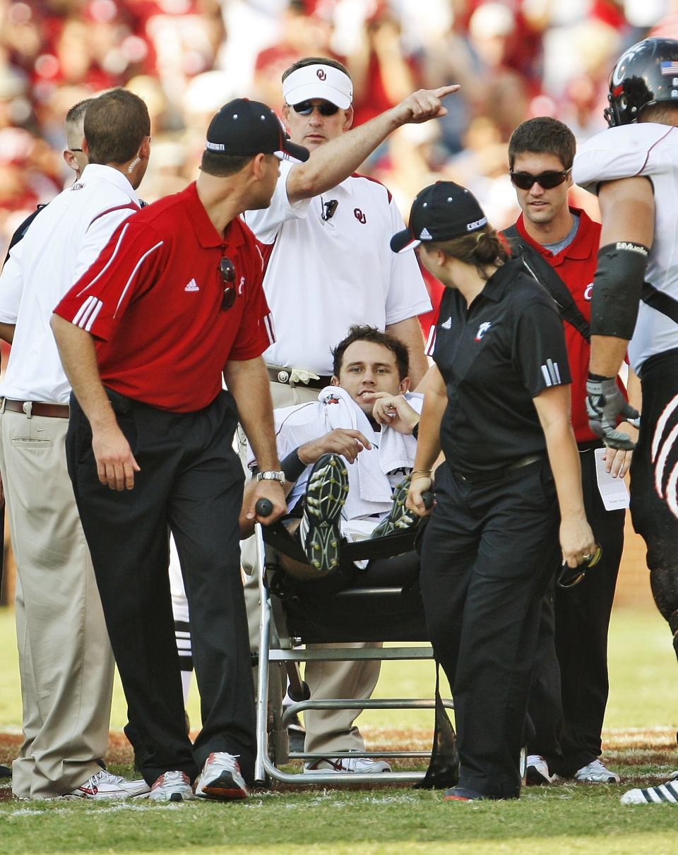 Cincinnati quarterback Dustin Grutza, center, is wheeled off the field after being injured in the fourth quarter of an NCAA college football game against Oklahoma, in Norman, Okla., Saturday, Sept. 6, 2008. Oklahoma won the game 52-26. (AP Photo/Sue Ogrocki)