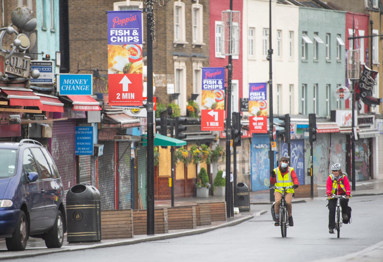 Cyclists ride past shuttered shops on Camden High Street, in north London, as the UK continues in lockdown to help curb the spread of the coronavirus.