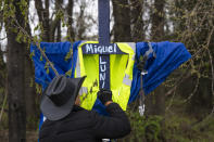 Roberto Marquez, an artist from Dallas, paints the name of a construction worker on a cross as part of a memorial near Fort Armistead Park, in Baltimore, Saturday, April 6, 2024, to honor the workers who lost their lives in the collapse of the Francis Scott Key Bridge. (Kaitlin Newman/The Baltimore Banner via AP)