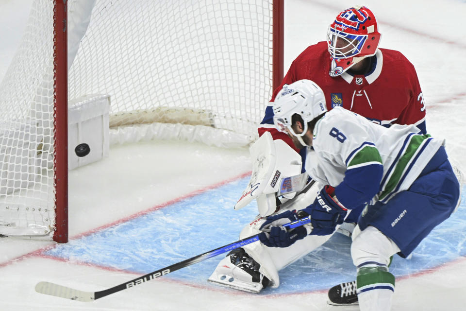 Vancouver Canucks' Conor Garland (8) scores against Montreal Canadiens goaltender Jake Allen, top, during second-period NHL hockey game action in Montreal, Sunday, Nov. 12, 2023. (Graham Hughes/The Canadian Press via AP)