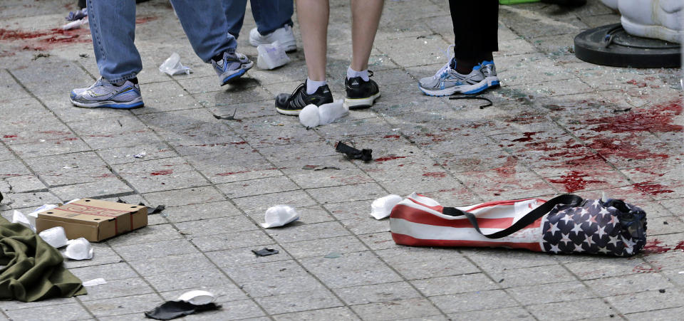 FILE - In this April 15, 2013 file photo, blood covers the sidewalk on Boylston Street, at the site where a bomb exploded during the 2013 Boston Marathon in front of the Marathon Sports store in Boston. At right foreground is a folding chair with the design of an American flag on the cover. In the course of a year, limbs have been replaced, psyches soothed, the wounds sustained in a moment at the marathon’s finish line have at least begun to heal. At the same time, a city shaken by an act of terrorism has returned to its usual rhythms - sadder, but some say stronger, as well. (AP Photo/Charles Krupa, File)