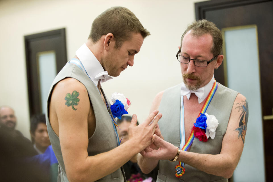 Alexander Emereev, right, slips a wedding band on his partner Dmitry Zaytsev, both of Russia, during their civil marriage ceremony in Buenos Aires, Argentina, Tuesday, Feb. 25, 2014. The two men, who are from Sochi, planned to apply for political asylum after their ceremony at the civil registry in Buenos Aires. (AP Photo/Victor R. Caivano)