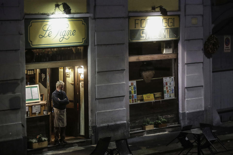 The owner of a restaurant stands in the doorway of the his establishment in the Naviglio Grande district, in Milan, Italy, Friday, Oct. 23, 2020. (AP Photo/Luca Bruno)