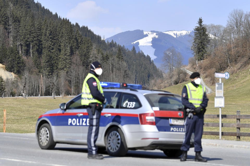 Police officers blog the road to the skying resort Saalbach Hinterglemm, Austrian province of Salzburg, Friday, April 3, 2020 after the city was quarantined.The Austrian government has moved to restrict freedom of movement for people, in an effort to slow the onset of the COVID-19 coronavirus. (AP Photo/Kerstin Joensson)