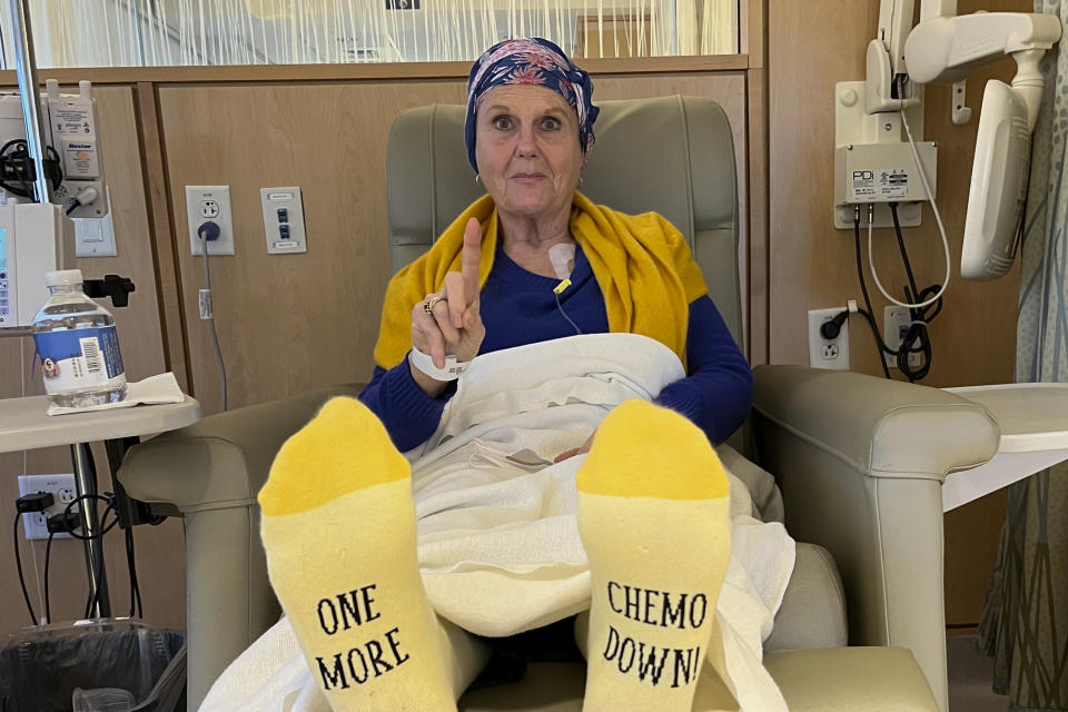 Lynda Shannon Bluestein wears socks with "One More Chemo Down" on the soles prior to a cancer medicine infusion, Feb. 24, 2023, in Fairfield, Conn. (Paul Bluestein photo via AP)