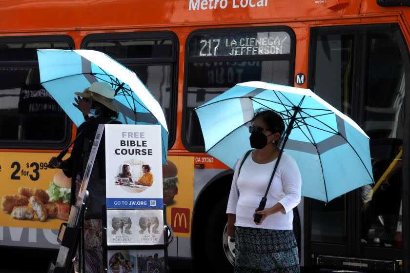 HOLLYWOOD, CA - SEPTEMBER , 3, 2022 - - A pair of Jehovah Witnesses enjoy the shade of their umbrellas during a heatwave in Hollywood on September 3, 2022. Saturday and Sunday will see "high" and "very high" heat levels in many areas, said Tom Fisher, a meteorologist with the National Weather Service in Oxnard. But Sunday will probably bring the heat wave's most intense temperatures. (Genaro Molina / Los Angeles Times)