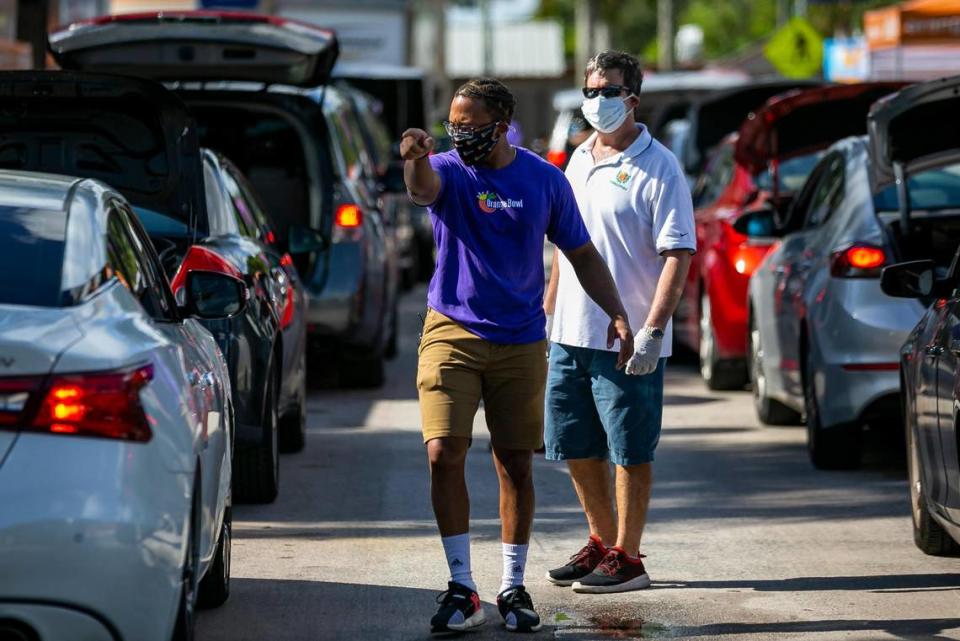 Jared Romance, 30, directs cars during a drive-thru distribution event at Joseph C. Carter Park in Fort Lauderdale, Florida on Saturday, Aug. 8, 2020. Volunteers distributed food, sanitation items, backpacks and back-to-school necessities during the 8th Annual Sunshine Health Orange Bowl Family, Fun & Fit Day drive-thru only event.