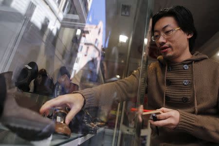 Renato Gu, 31, works inside his women's shoe and accessory shop in Rome November 21, 2014. Picture taken November 21, 2014. REUTERS/Tony Gentile