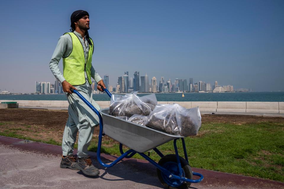 A Pakistani migrant laborer works on the corniche Oct. 19, 2022. The World Cup has thrown an uncomfortable spotlight on Qatar’s labor system, which links workers’ visas to employers and keeps wages low for workers toiling in difficult conditions.