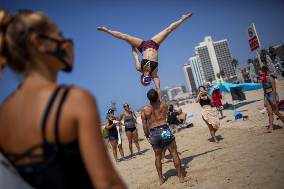 Acrobats perform as they wear face masks during a protest against government's decision to close beaches during the three-week nationwide lockdown due to the coronavirus pandemic, in Tel Aviv, Israel, Saturday, Sept 19, 2020. Israel went back into a full lockdown on Friday to try to contain a coronavirus outbreak that has steadily worsened for months as its government has been plagued by indecision and infighting. (AP Photo/Oded Balilty)
