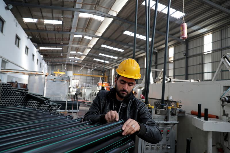 A Palestinian man works in Al-Siksik factory for plastic pipes in Gaza City