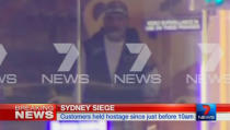 A man is seen standing behind the window of the Lindt cafe, where hostages are being held, in this still image taken from video from Australia's Seven Network on December 15, 2014. REUTERS/Reuters TV via Seven Network/Courtesy Seven Network