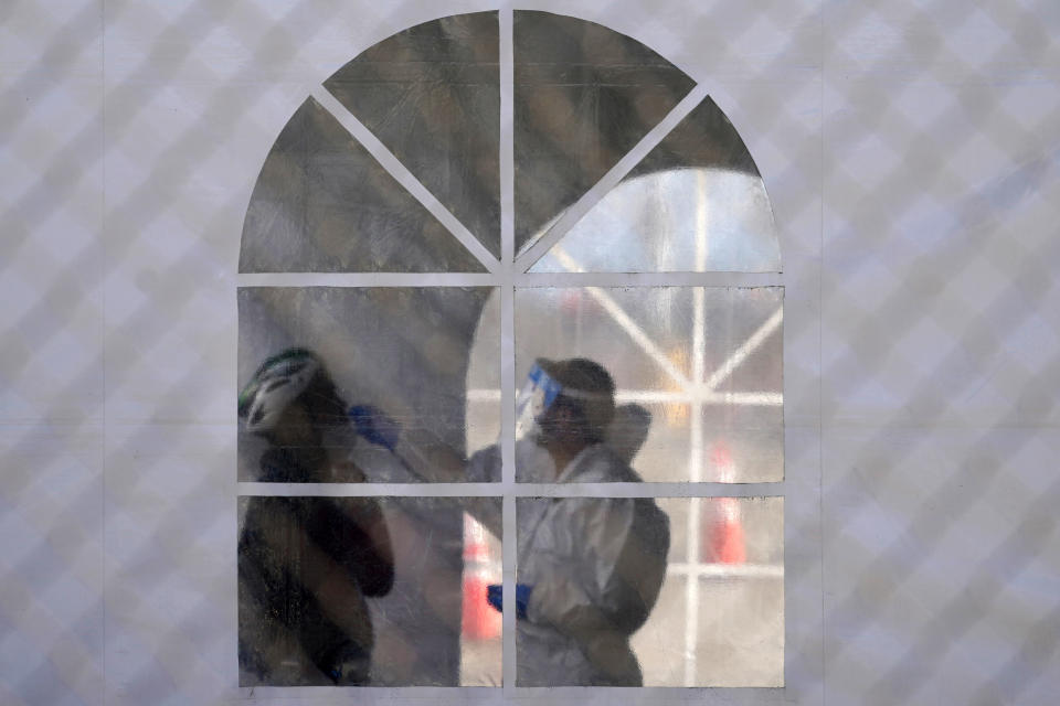 A health care worker gives a test at a COVID-19 testing site during the coronavirus outbreak in San Francisco, Monday, Nov. 16, 2020. (AP Photo/Jeff Chiu)