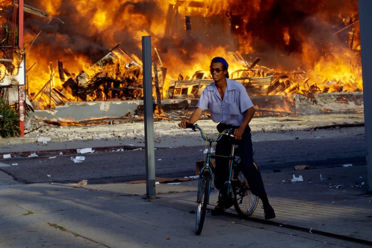 Man on a bicycle near burning building on April 30, 1992. (Photo: David Butow)