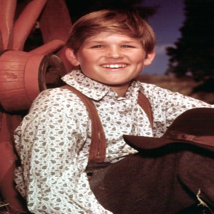 closeup of his young character sitting in hay and wearing suspenders