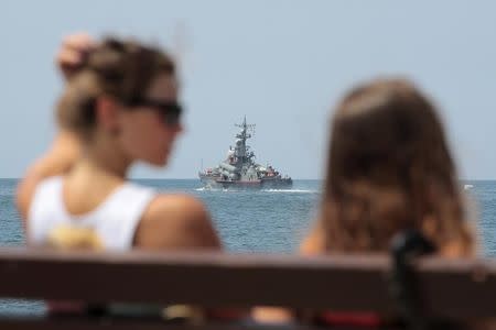 People spend time at a quay, with a Russian warship seen in the background, in Sevastopol in Crimea August 8, 2014. REUTERS/Pavel Rebrov