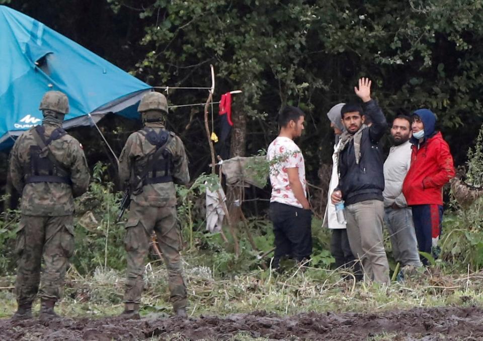 Polish border guard officers stand guard next to a group of migrants stranded on the border between Belarus and Poland (REUTERS)