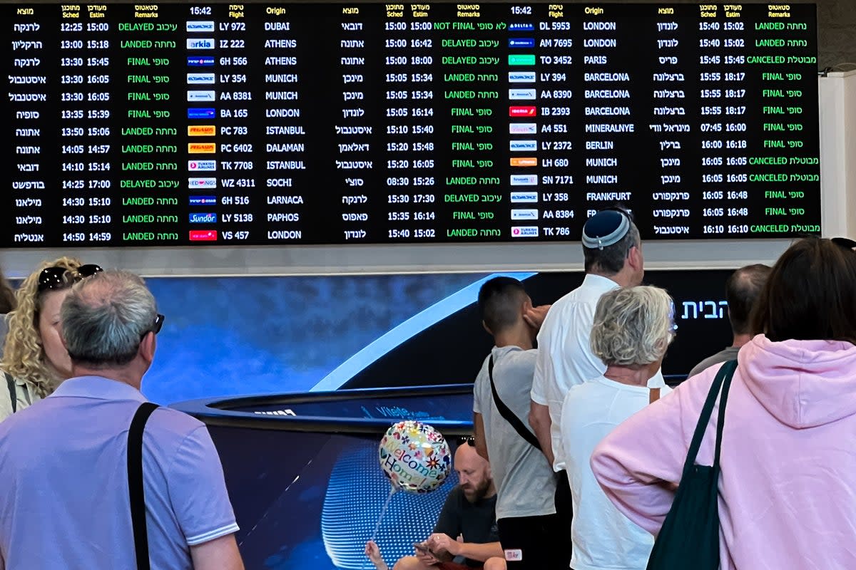 People looking at cancelled flights on a departure board at the airport in Tel Aviv  (Getty )