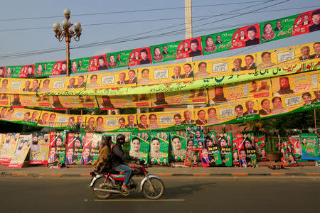 Residents ride on bike past election campaign signs along a road in Lahore, Pakistan September 10, 2017. REUTERS/Mohsin Raza