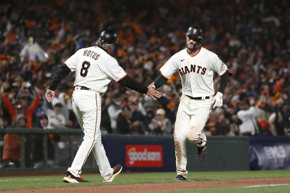 San Francisco Giants' Kris Bryant, right, is congratulated by San Francisco Giants third base coach Ron Wotus (8) after hitting a home run against the Los Angeles Dodgers during the seventh inning of Game 1 of a baseball National League Division Series Friday, Oct. 8, 2021, in San Francisco. (AP Photo/Jed Jacobsohn)