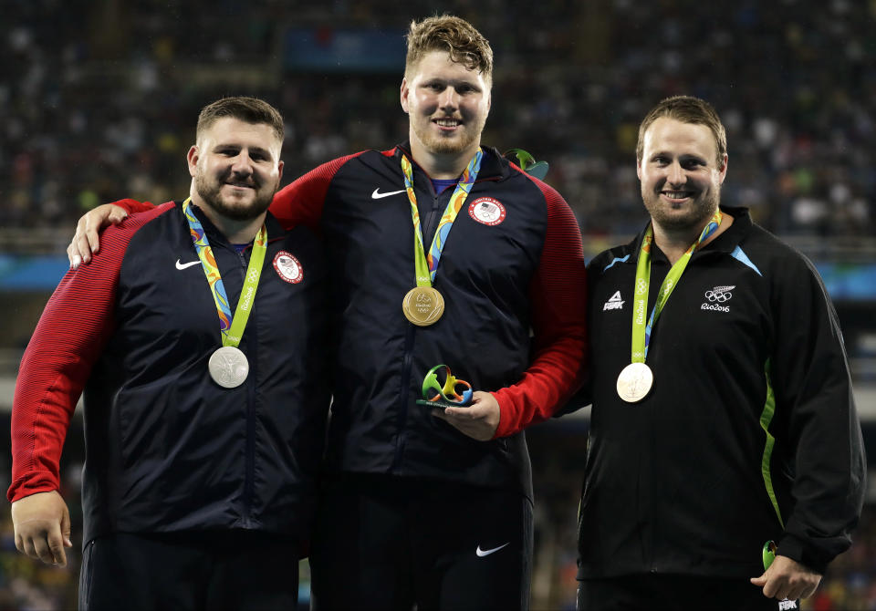 FILE - From left, shot put silver medallist United States' Joe Kovacs, compatriot and gold medal winner Ryan Crouser and bronze medallist New Zealand's Tomas celebrate on the podium during the athletics competitions of the 2016 Summer Olympics at the Olympic stadium in Rio de Janeiro, Brazil, Thursday, Aug. 18, 2016. Every issue consuming college sports right now — NIL, potential player salaries, conference realignment, TV deals, the expansion of the football playoff and maybe the basketball tournament — will affect how the plethora of crew, gymnastics, wrestling and dozens of other Olympic sports teams do at the games for years to come. (AP Photo/Dmitri Lovetsky, File)