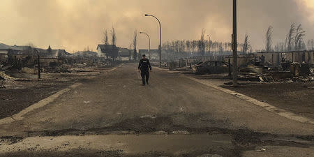 A Mountie surveys the damage on a street in Fort McMurray, Alberta, Canada in this twitter image posted on May 5, 2016. Courtesy RCMP Alberta/Handout via REUTERS