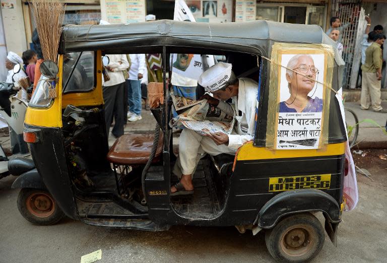 A supporter of Indian activist and Aam Aadmi Party (AAP) candidate Medha Patkar reads a newspaper as he sits in an auto rickshaw outside the party office in Mumbai, April 14, 2014