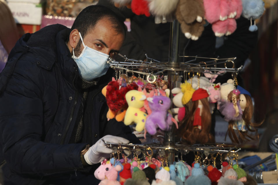 A street vendor wearing a face mask waits for customer in western Tehran, Iran, Saturday, Feb. 29, 2020. Iran is preparing for the possibility of "tens of thousands" of people getting tested for the new coronavirus as the number of confirmed cases spiked again Saturday, Health Ministry spokesman Kianoush Jahanpour said, underscoring the fear both at home and abroad over the outbreak in the Islamic Republic. (AP Photo/Vahid Salemi)