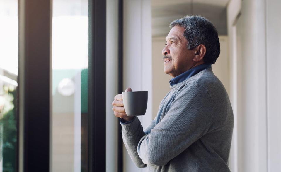 Someone is holding a mug and looking out a window, thoughtfully. 