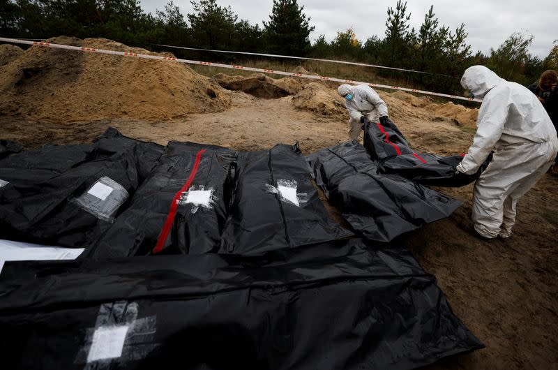 Forensics lie down a body of an army officer they exhumed from, what Ukrainians said, a mass grave, in the newly recaptured town of Lyman