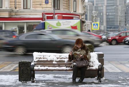 A woman sits on a bench and reads a magazine on a street in central Moscow, January 26, 2015. REUTERS/Maxim Zmeyev