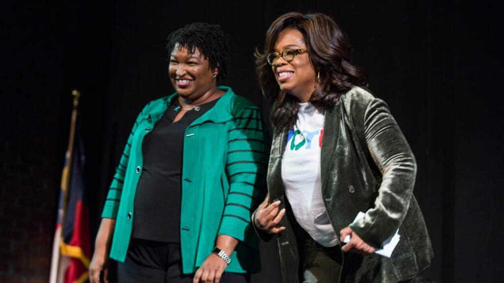 Oprah Winfrey and Georgia Democratic Gubernatorial candidate Stacey Abrams greet the audience during a town hall style event at the Cobb Civic Center on November 1, 2018 in Marietta, Georgia. Winfrey travelled to Georgia to campaign with Abrams ahead of the mid-term election. (Photo by Jessica McGowan/Getty Images)