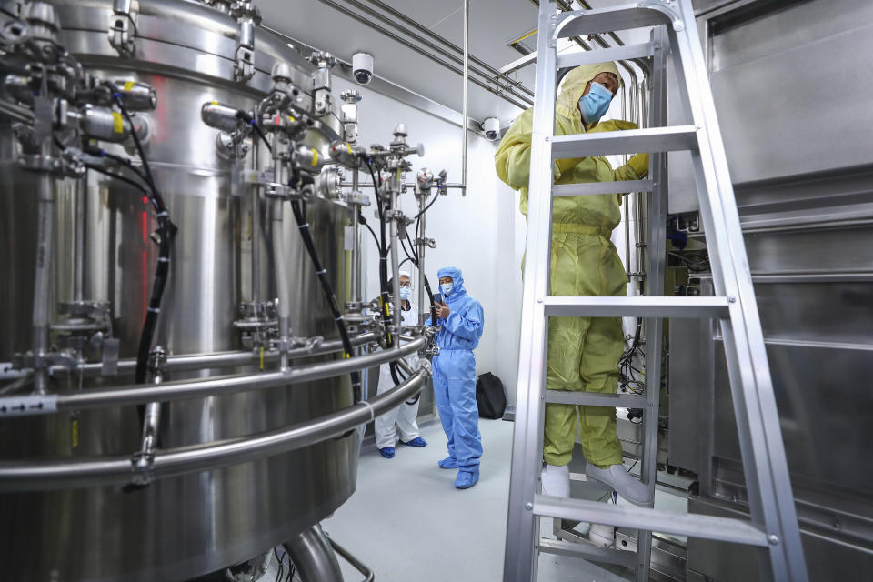 In this April 11, 2020, photo released by Xinhua News Agency, staff members check and clean equipments at a vaccine production plant of SinoPharm in Beijing. In the global race to make a coronavirus vaccine, the state-owned Chinese company is boasting that it gave its employees, including top executives, experimental shots even before the government OK'd testing in people. (Zhang Yuwei/Xinhua via AP)