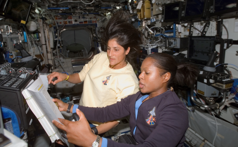 NASA astronauts Joan Higginbotham (foreground) and Suni Williams refer to a procedures checklist as they work the controls of Canadarm 2 in December 2006 aboard the International Space Station.