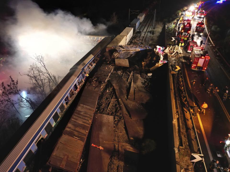 Smoke rises from trains as firefighters and rescuers operate after a collision near Larissa city, Greece, early Wednesday, March 1, 2023. The collision between a freight and passenger train occurred near Tempe, some 380 kilometers (235 miles) north of Athens, and resulted in the derailment of several train cars. (AP Photo/Vaggelis Kousioras)