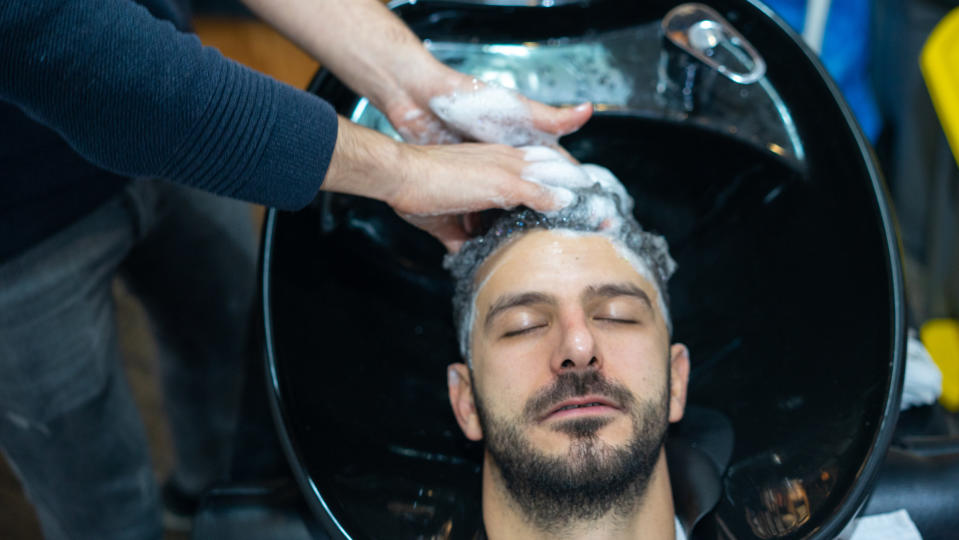 A man receiving a shampoo from a salon worker