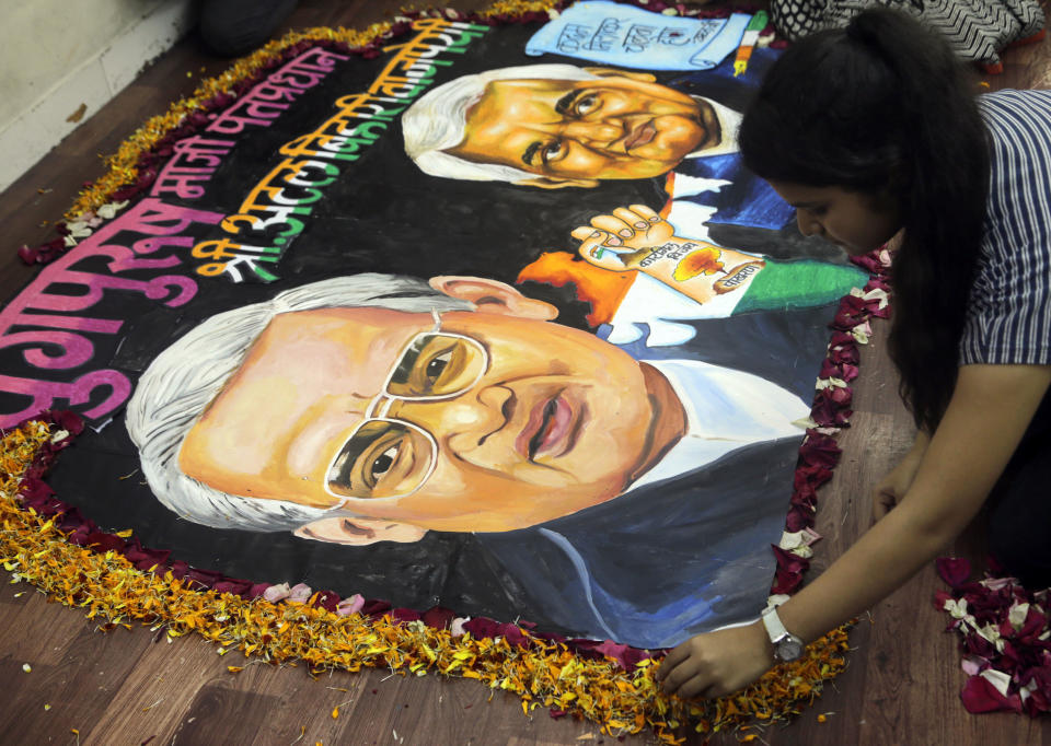 A student from an art school places flower petals around a painting of former Indian prime minister Atal Bihari Vajpayee in Mumbai, India, Thursday, Aug. 16, 2018. Vajpayee, who pursued both nuclear weapons and peace talks with Pakistan, died Thursday at age 93. (AP Photo/Rajanish Kakade)